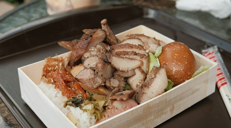 Packing lunch for work: a lunch box with white rice, sliced grilled meat, an egg and greens