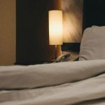 Khó ngủ về đêm: đèn ngủ ánh vàng dịu bên chiếc giường trải chăn trắng
