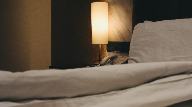 Trouble sleeping: a warm bedside lamp next to a bed with a white duvet